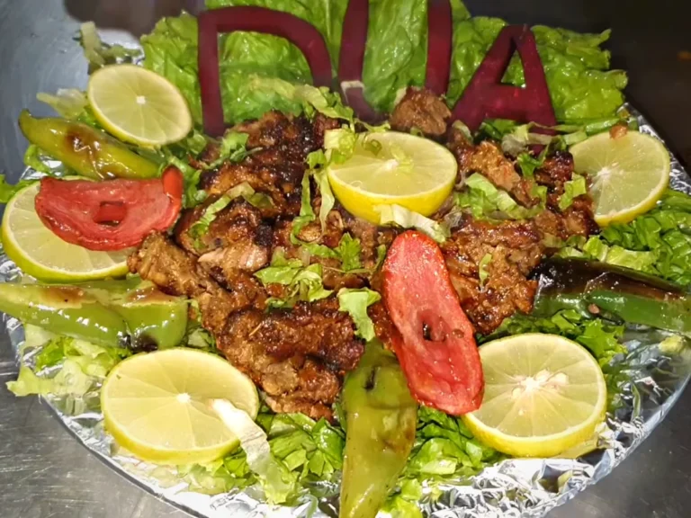 Beef bihari boti on a Dua Restaurant platter with lemon, grilled green chillies and tomato