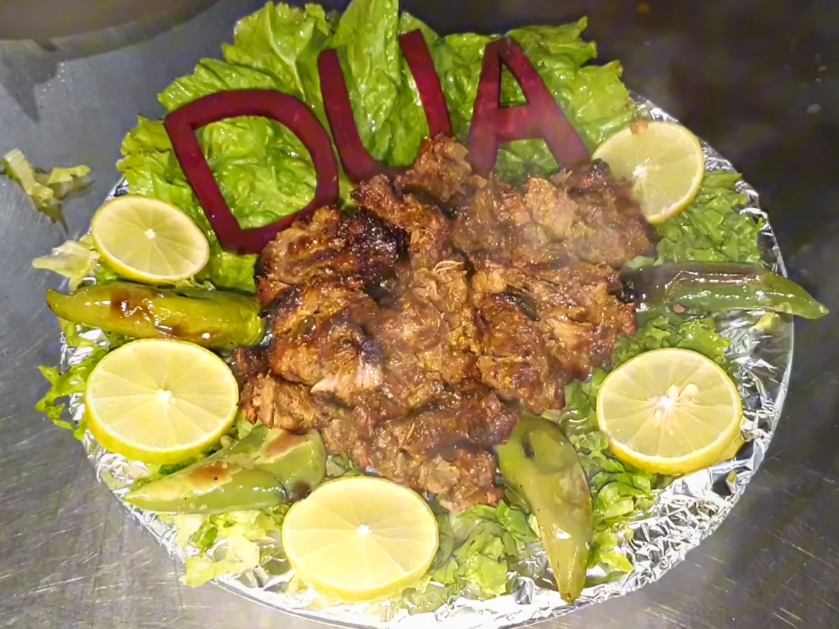 Bihari boti arranged on lettuce with lemon slices on a Dua platter