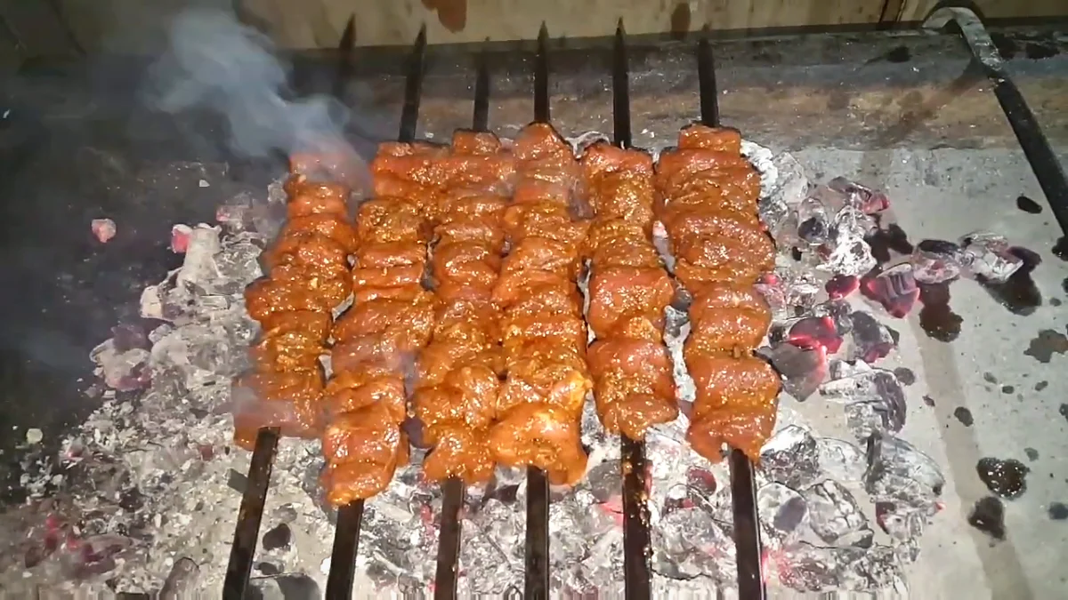 Beef Bihari kabab skewers cooking on a coal grill