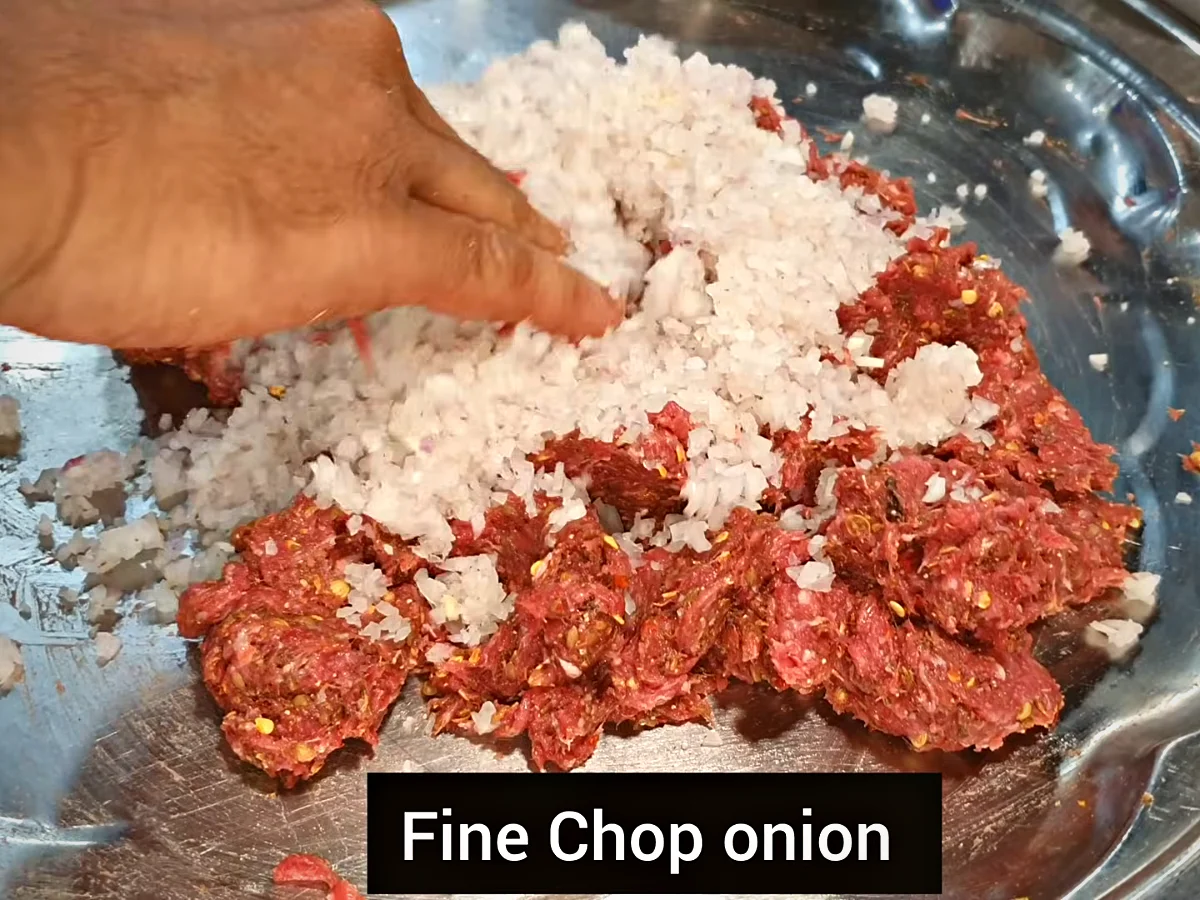Squeezed chopped onion being added to chapli kabab mince