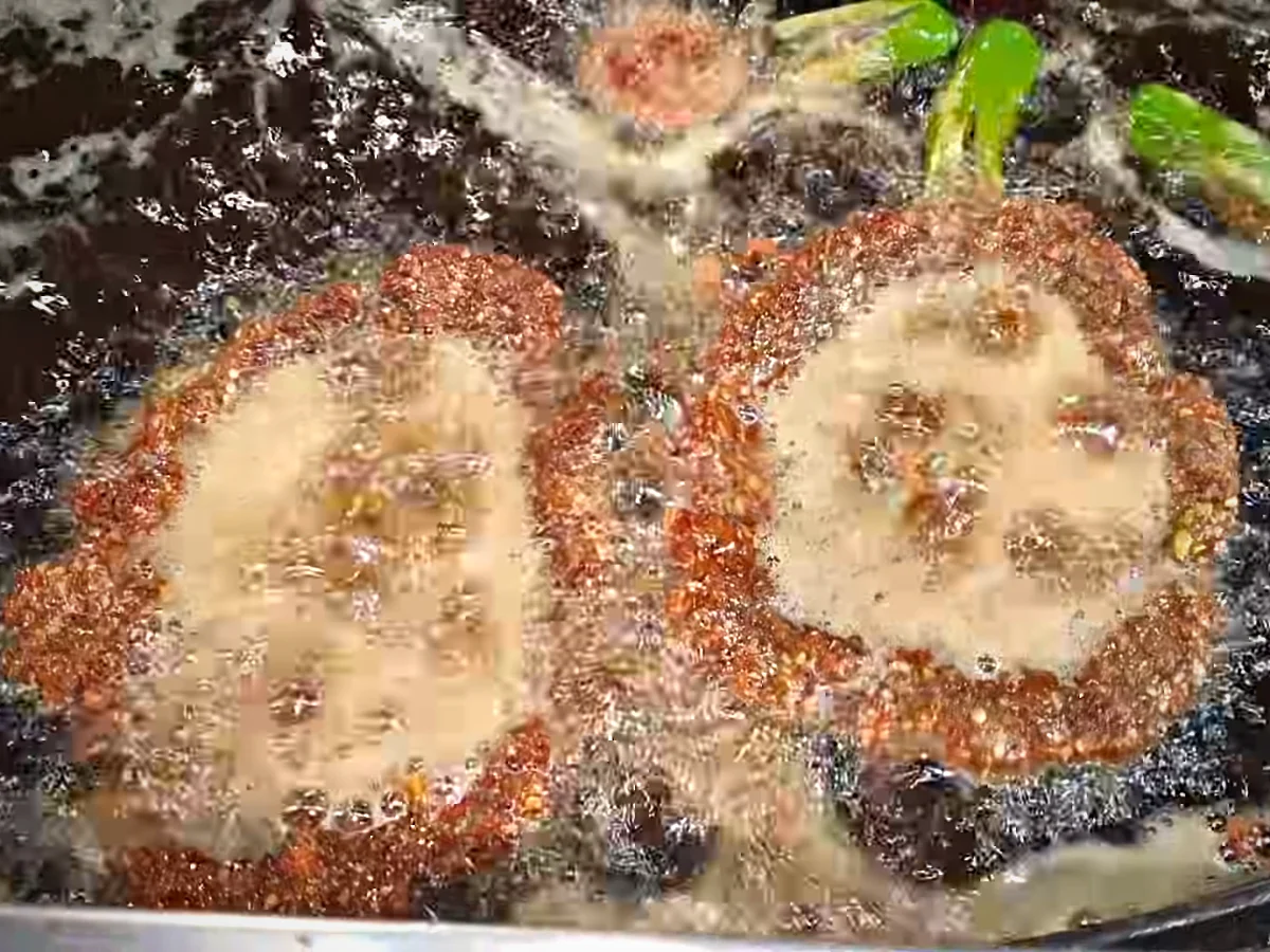 Two chapli kababs frying in hot oil with green chillies