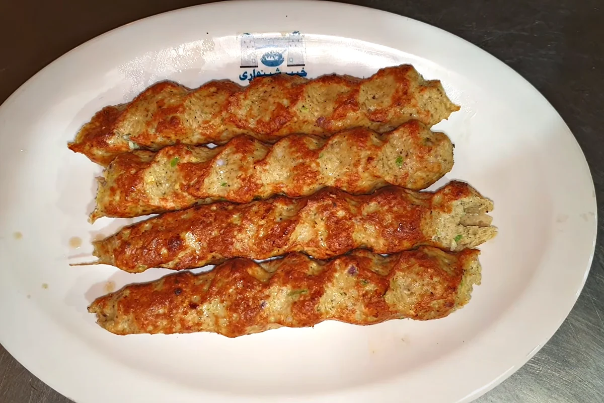 Four chicken reshmi kababs with a spiral pattern on a white plate