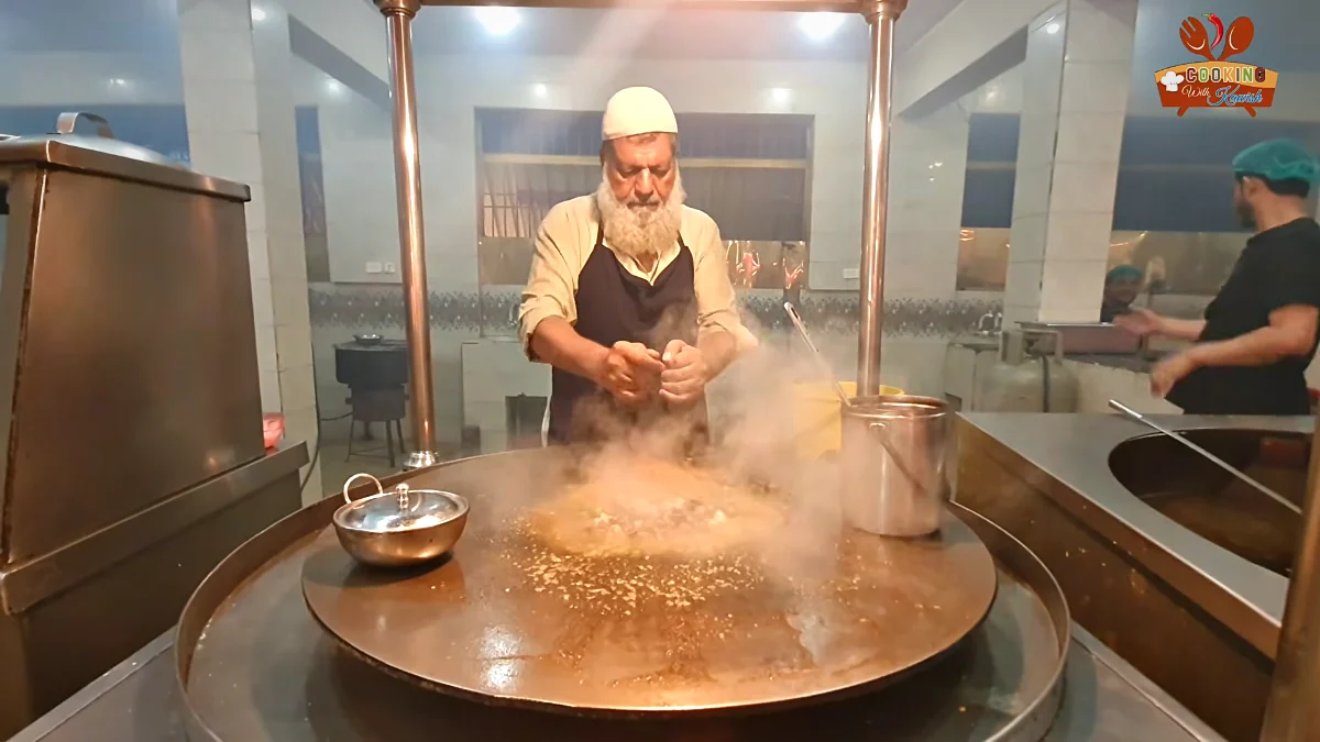 Cook chopping kata kat on the tawa with two metal blades