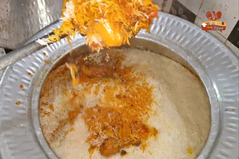 Degi chicken biryani with orange and white rice being served from the deg