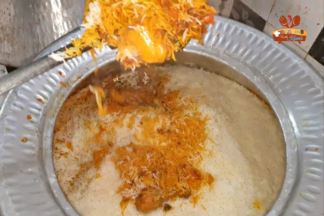 Degi chicken biryani with orange and white rice being served from the deg
