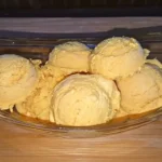 Scoops of homemade mango ice cream in a glass bowl