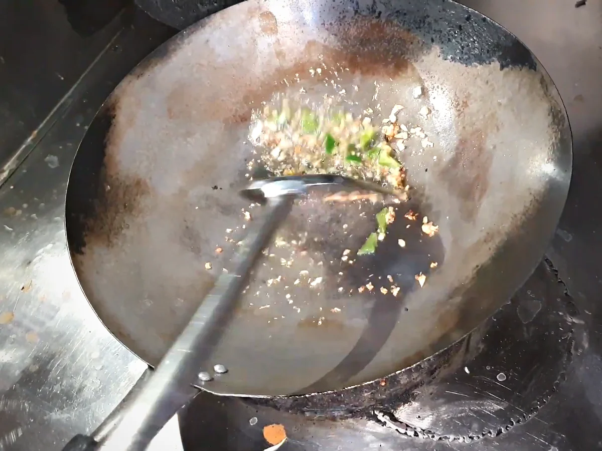 Boiled rice and green capsicum stir-fried with garlic in a wok