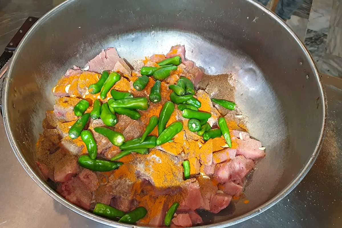 Whole green chillies and a yellow spice over chicken for reshmi kabab