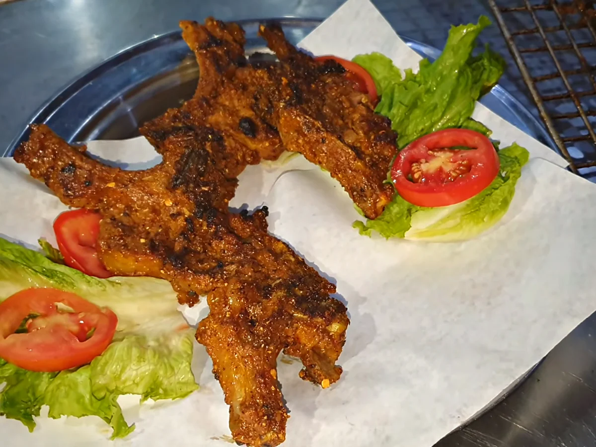 Grilled chatpata mutton chops on paper with lettuce and tomato