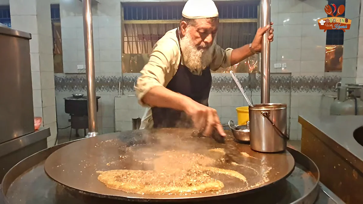 Cook at Khan Jee Restaurant making kata kat on a large tawa