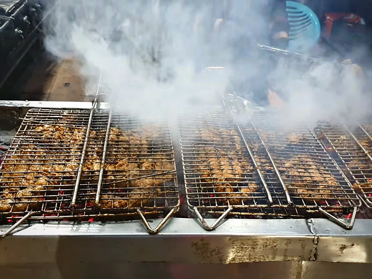 Mutton chops grilling over hot coals with thick smoke