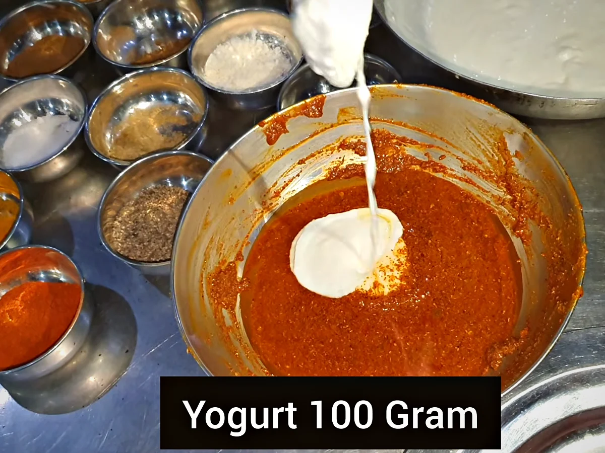 100 g yogurt being poured into the red spice paste for mutton chops