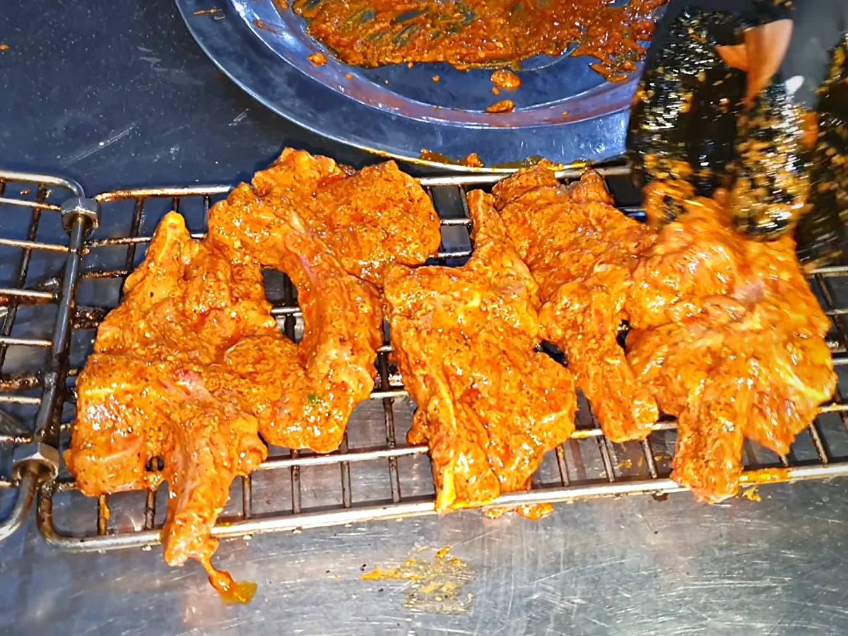 Marinated mutton chops arranged on a hinged BBQ grill rack
