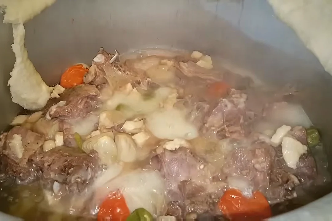 Mutton rosh ready in the pot, steaming, with lamb fat, tomatoes and potatoes