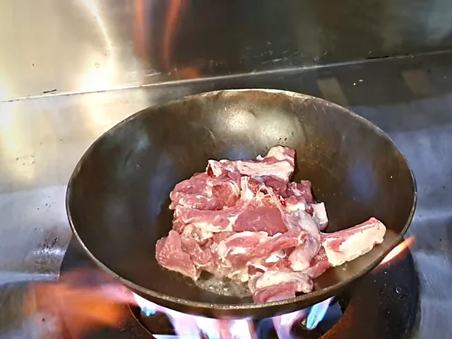 Raw mutton chops in an empty karahi on the flame