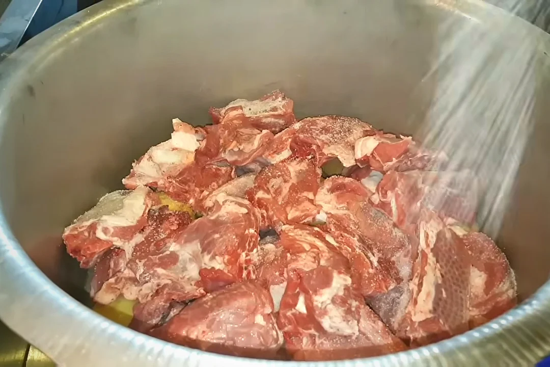 Salt being sprinkled over the second layer of mutton for rosh