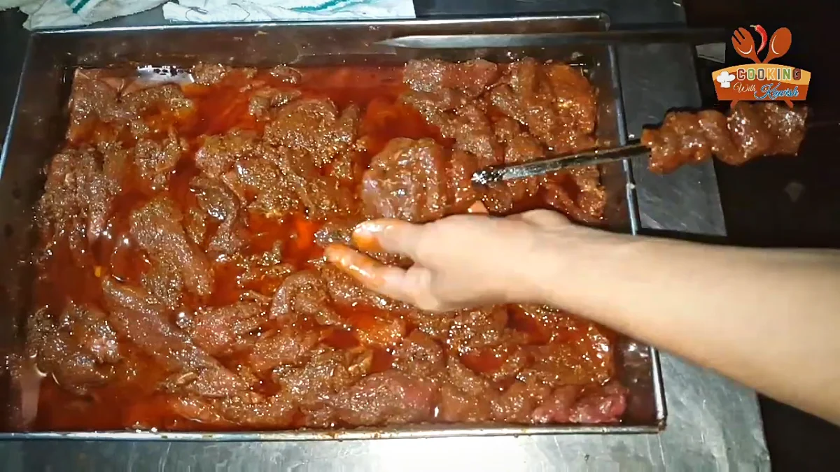 Threading marinated beef strips onto skewers for Bihari kabab