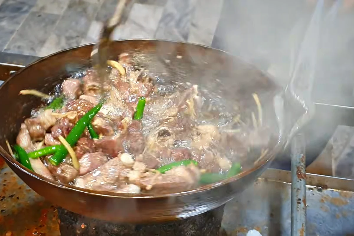 Small hot green chillies frying with mutton in the karahi