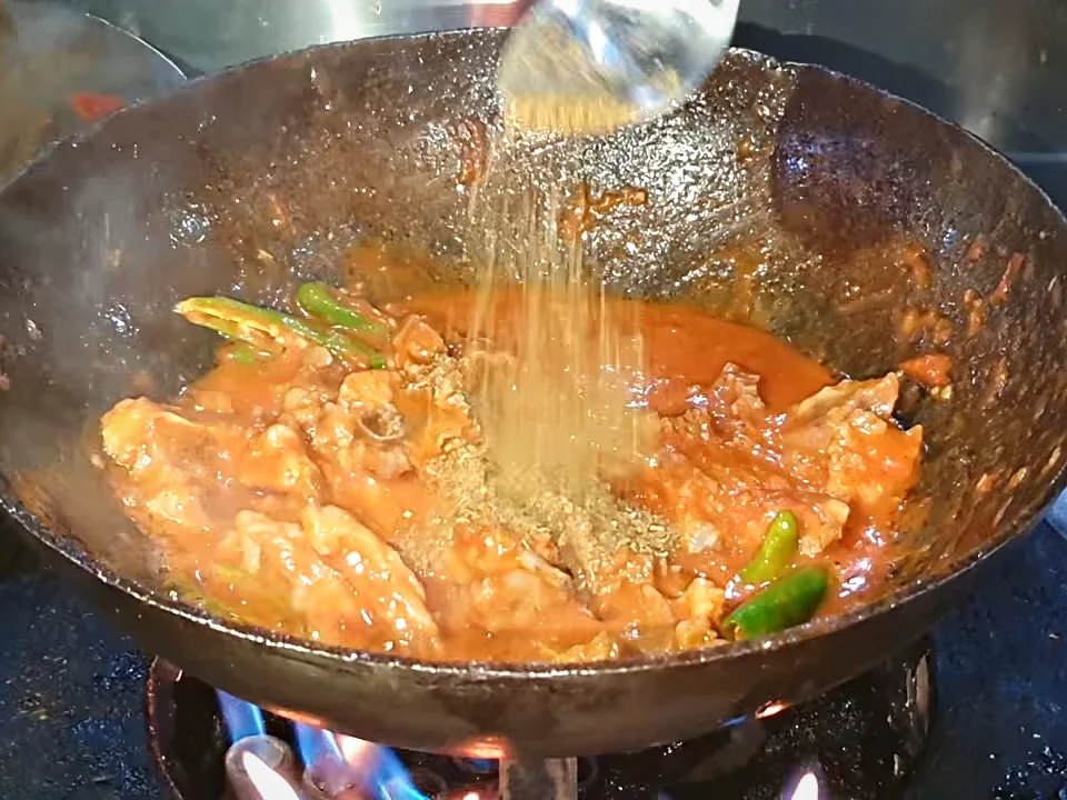 Ground spice mix being sprinkled over mutton chops karahi
