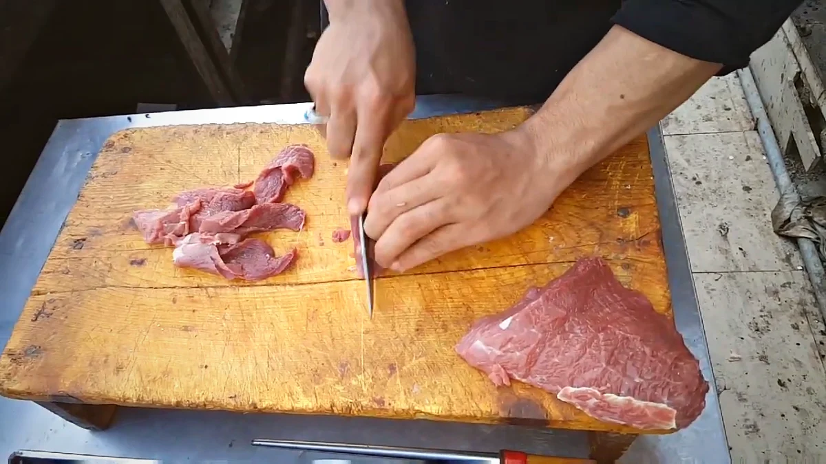 Cutting boneless beef into thin strips for Bihari kabab
