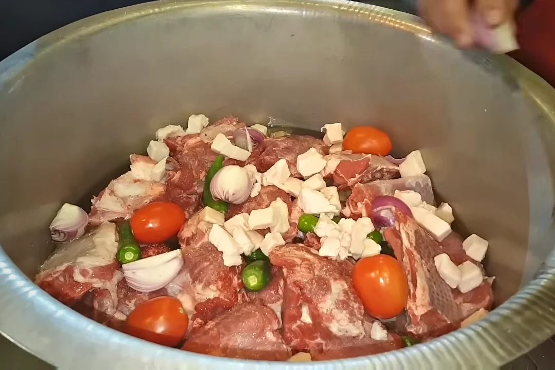 Whole tomatoes and onion on top of mutton rosh before sealing