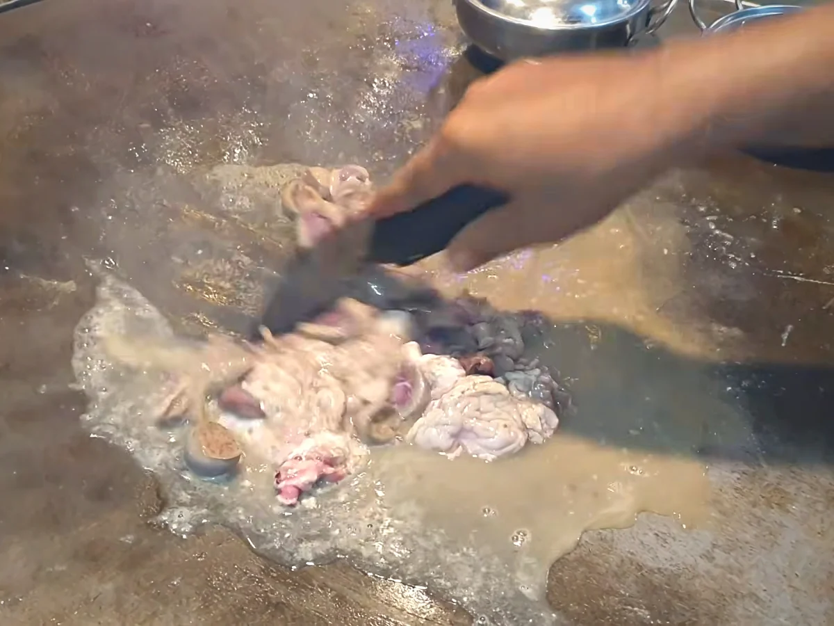 Goat heart and kidneys being washed with hot water on the tawa