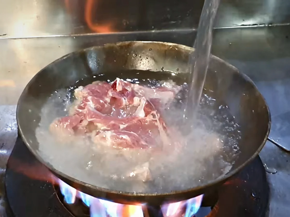 Water being poured over mutton chops in a karahi