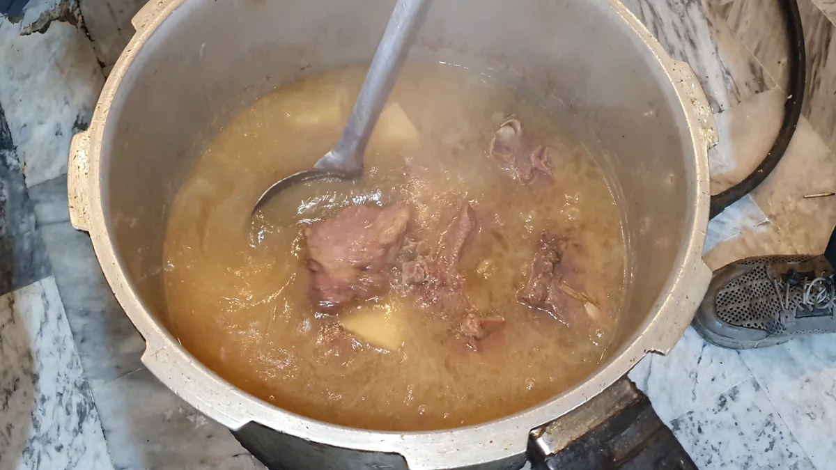 Cooked mutton in golden yakhni inside the open pressure cooker