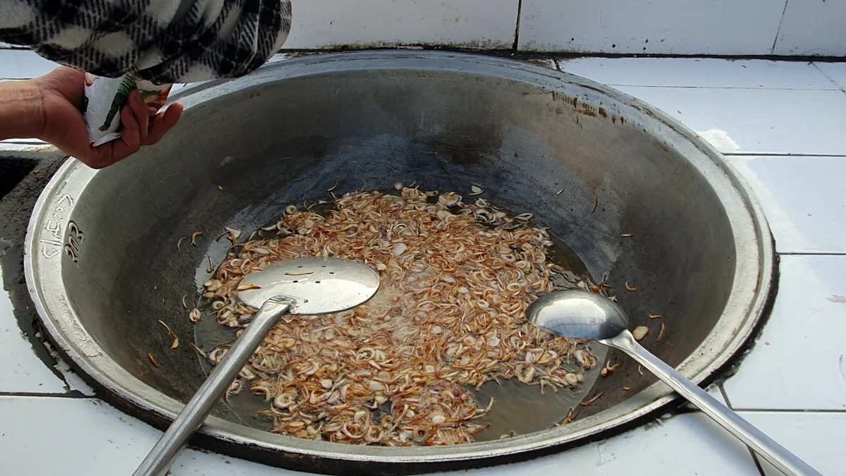 Sliced onions frying in oil in a large deg