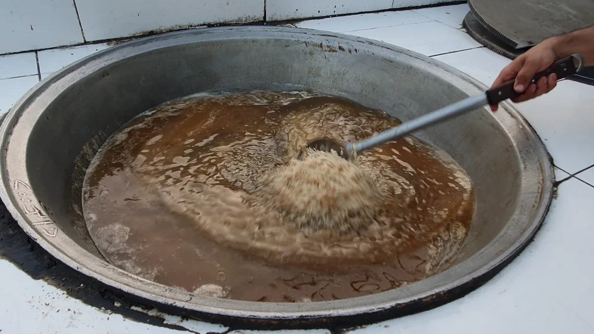 Rice cooking in the stock as the cook stirs it with a long ladle