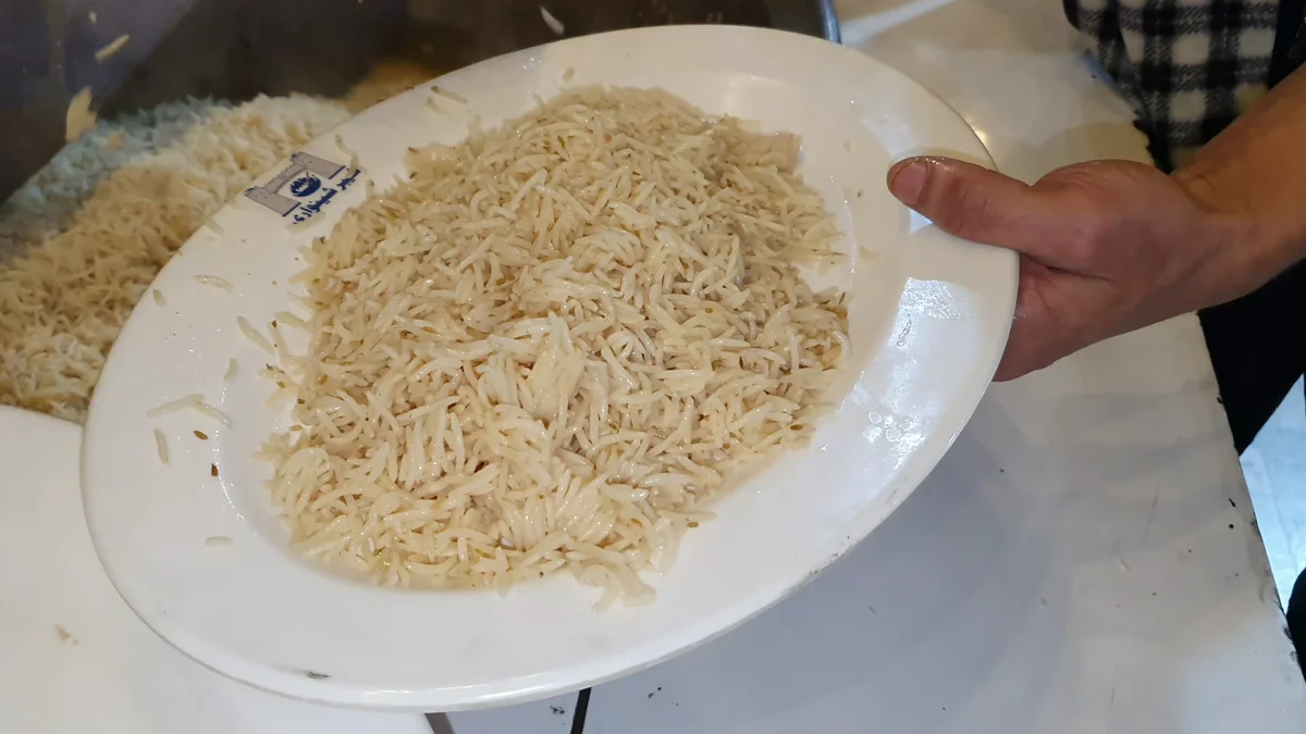 Plate of Afghani pulao rice held over the deg, ready to serve