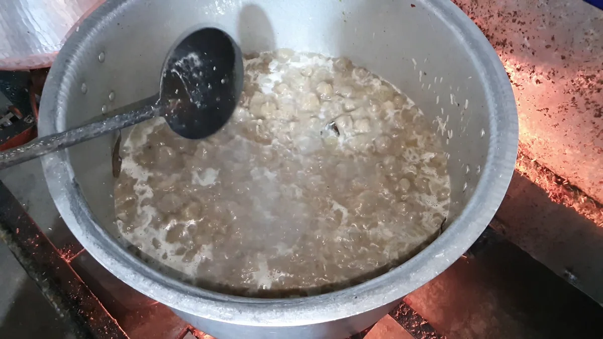 Rice cooking in the yakhni with a slotted ladle