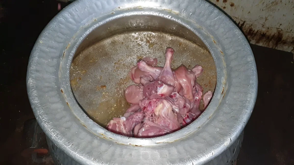 Raw chicken pieces going into the pot