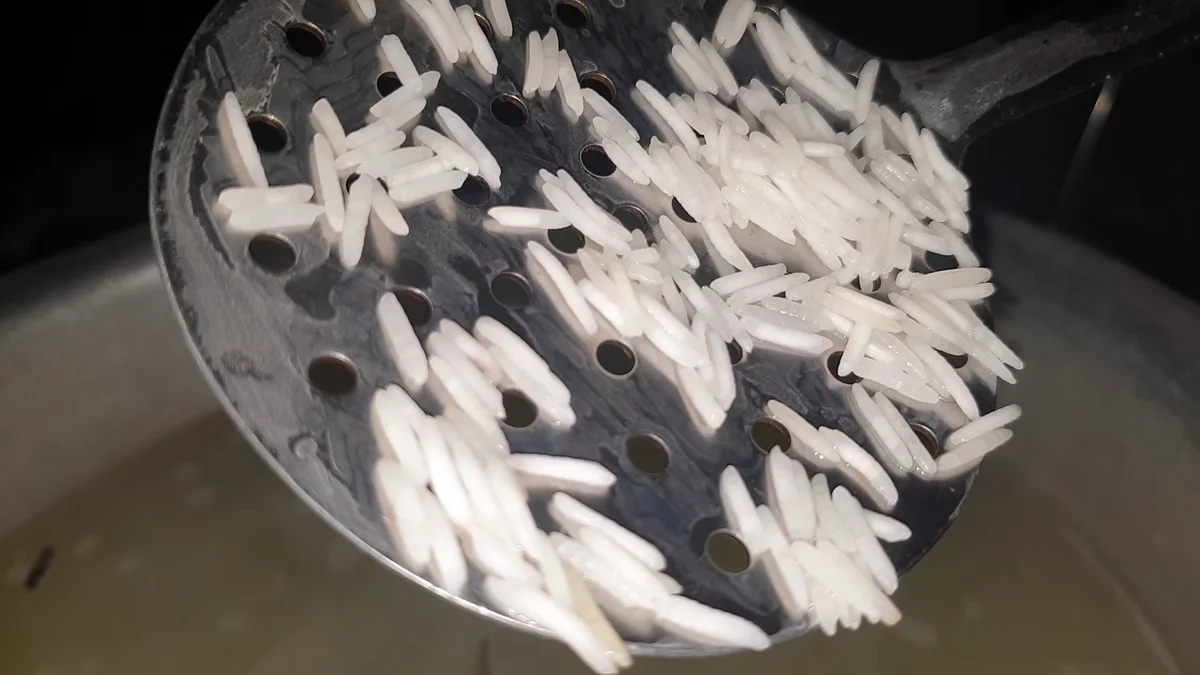 Par-boiled basmati rice lifted out with a slotted spoon