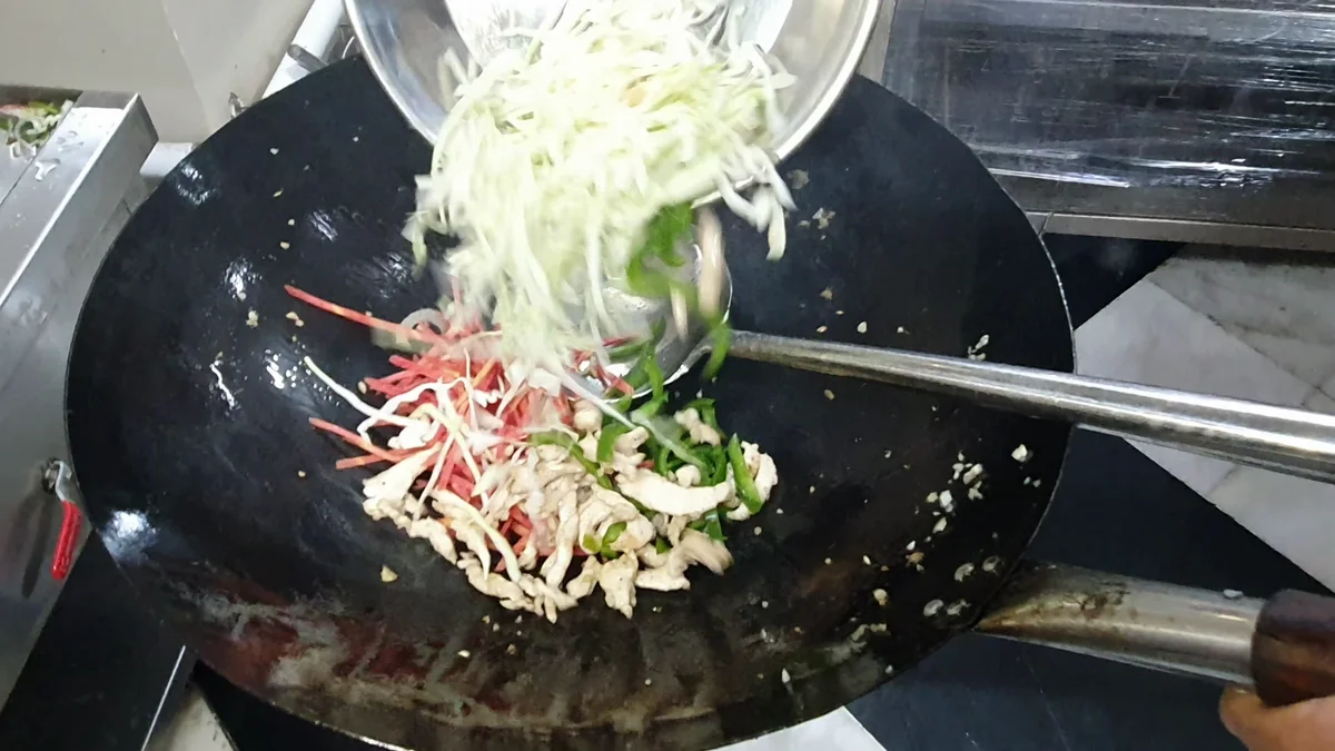 Vegetables and chicken going into the hot wok