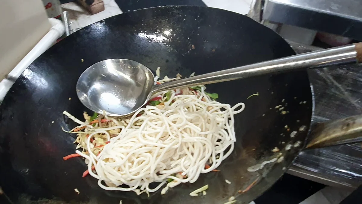 Boiled noodles added to the wok