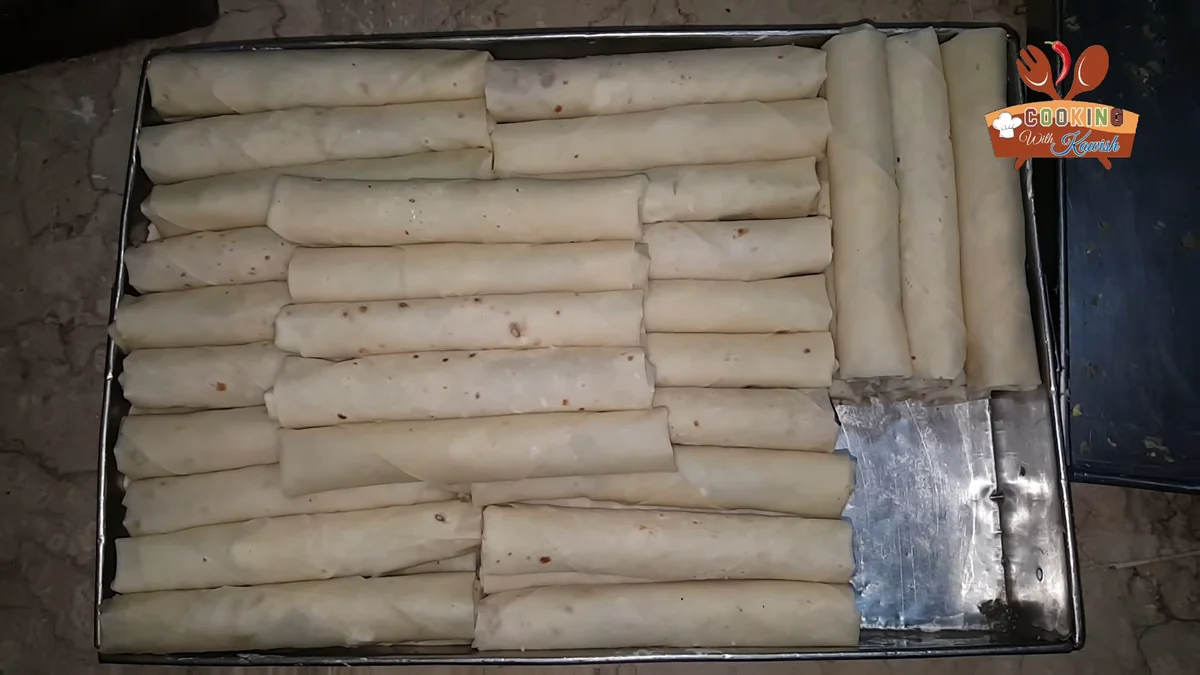 Rolled spring rolls lined up on a tray