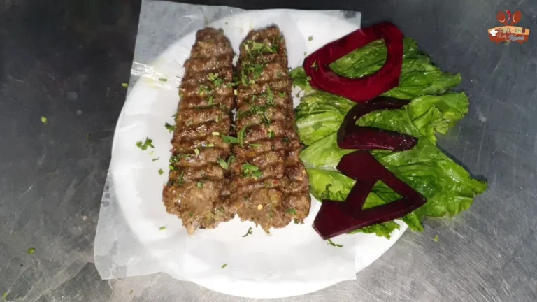 Two beef seekh kababs on a plate with lettuce and a DUA garnish