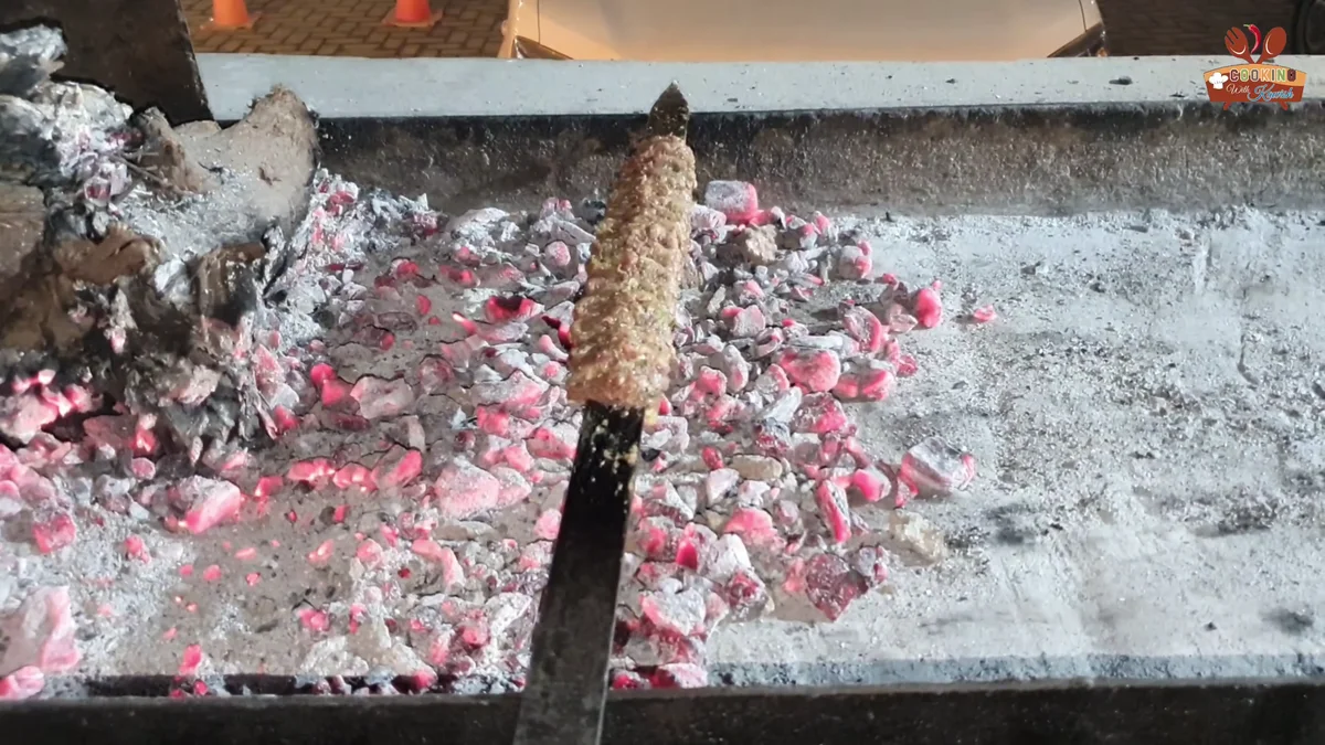 Seekh kabab on a long skewer over glowing charcoal