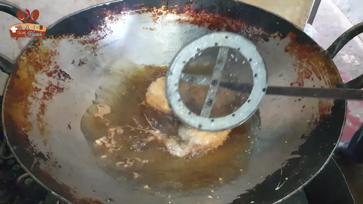 Lifting fried cutlets out of the oil with a strainer