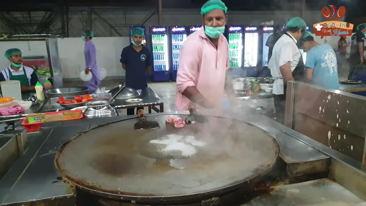 Cook at a large tawa in a restaurant kitchen