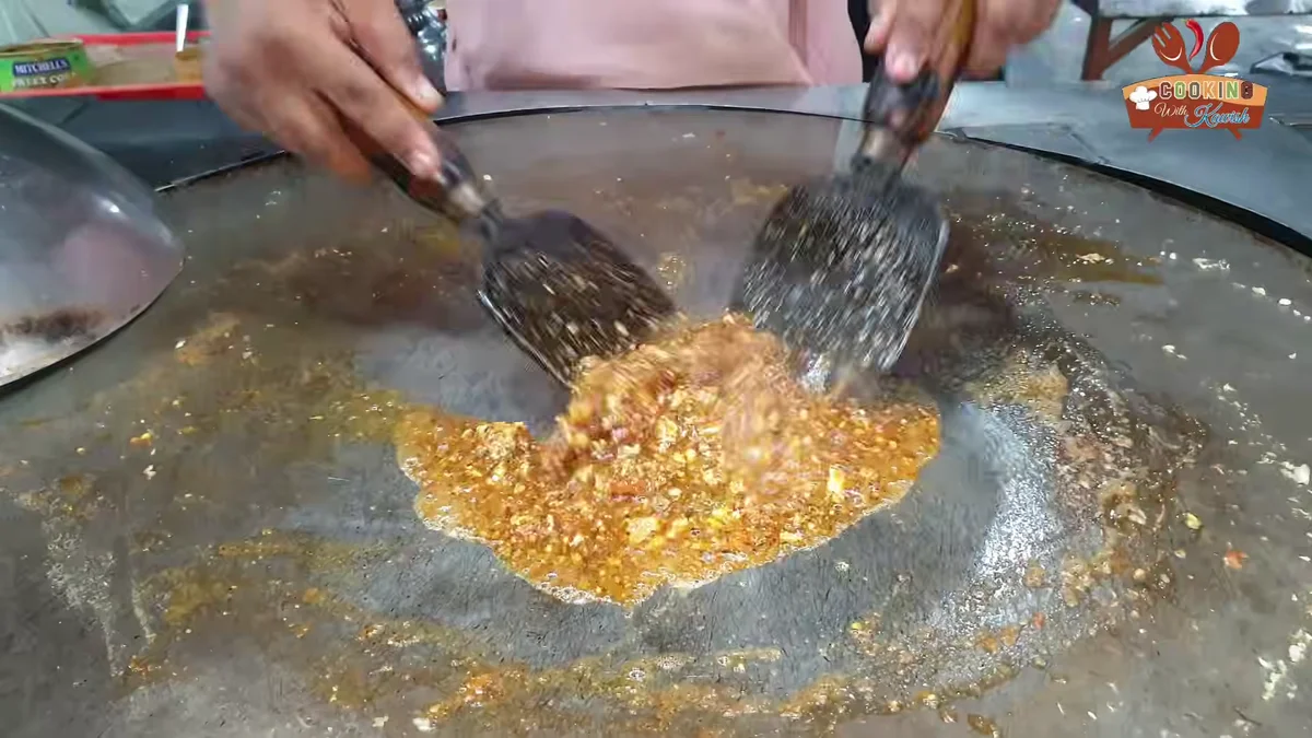 Brain masala being mixed with two spatulas