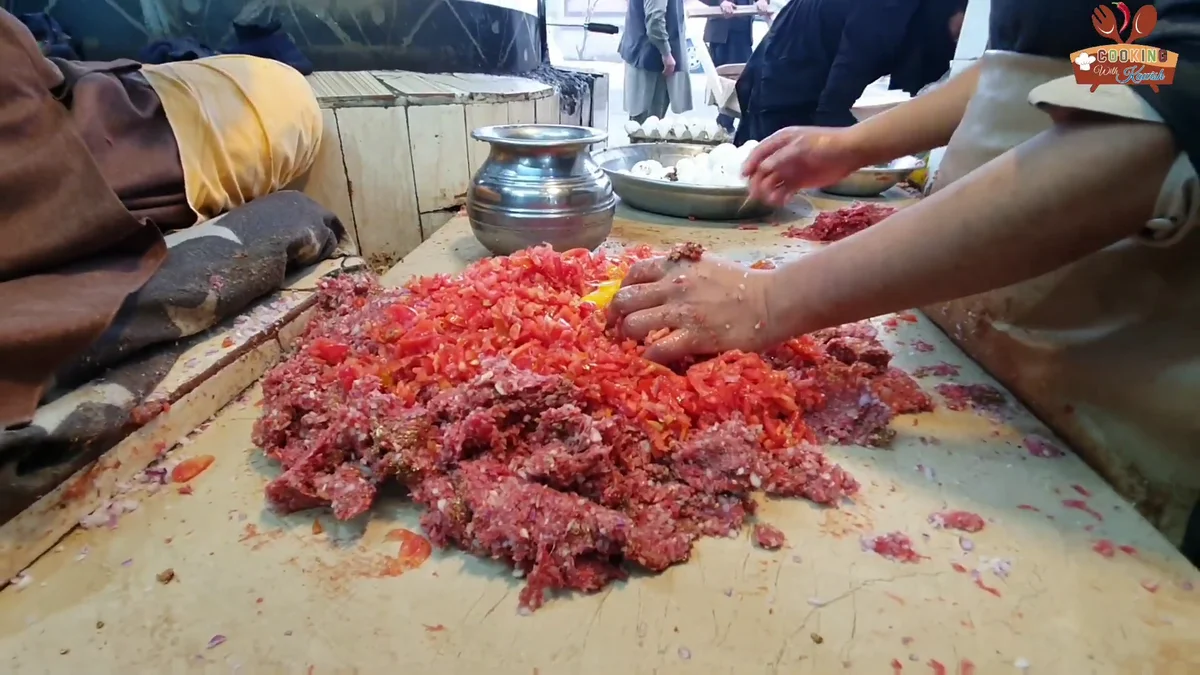 Red chilli powder being mixed into the mince
