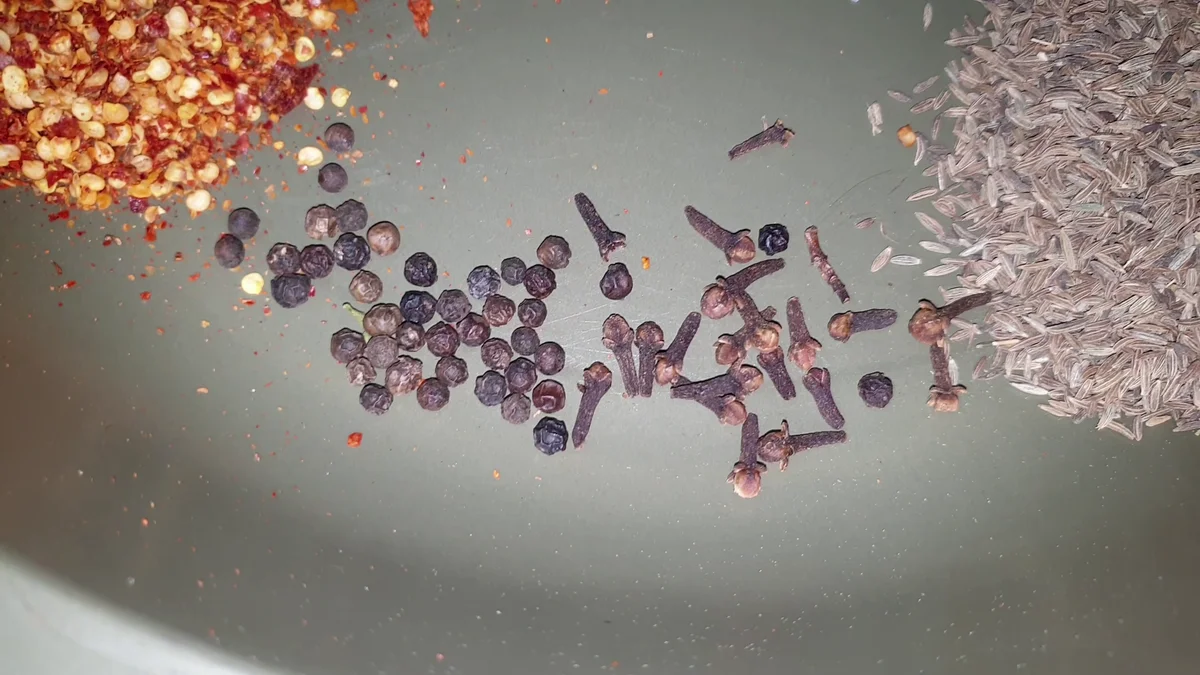 Whole spices: black peppercorns, cloves and cinnamon