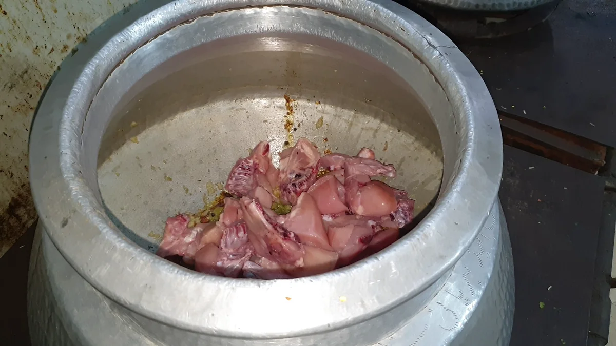 Raw chicken pieces added to the masala