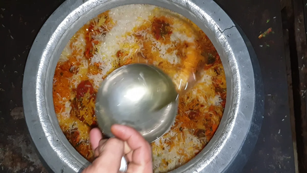 Cook at the biryani deg with a ladle after the dum