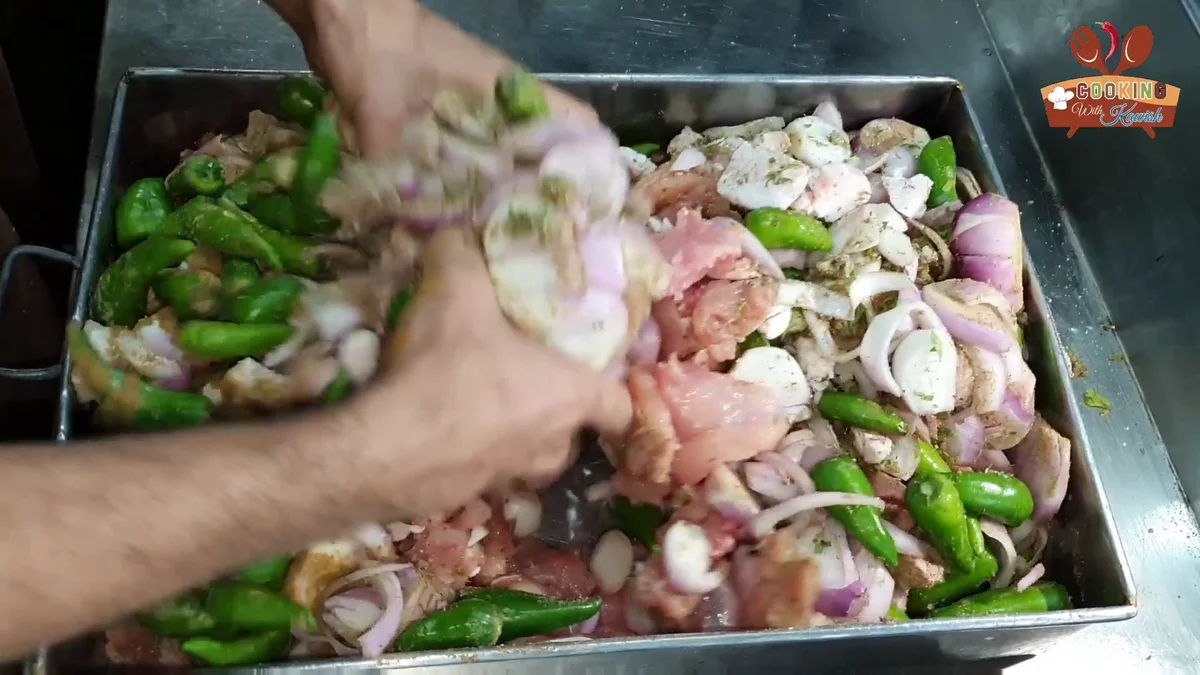 Mixing the chicken, onions and green chillies by hand before grinding