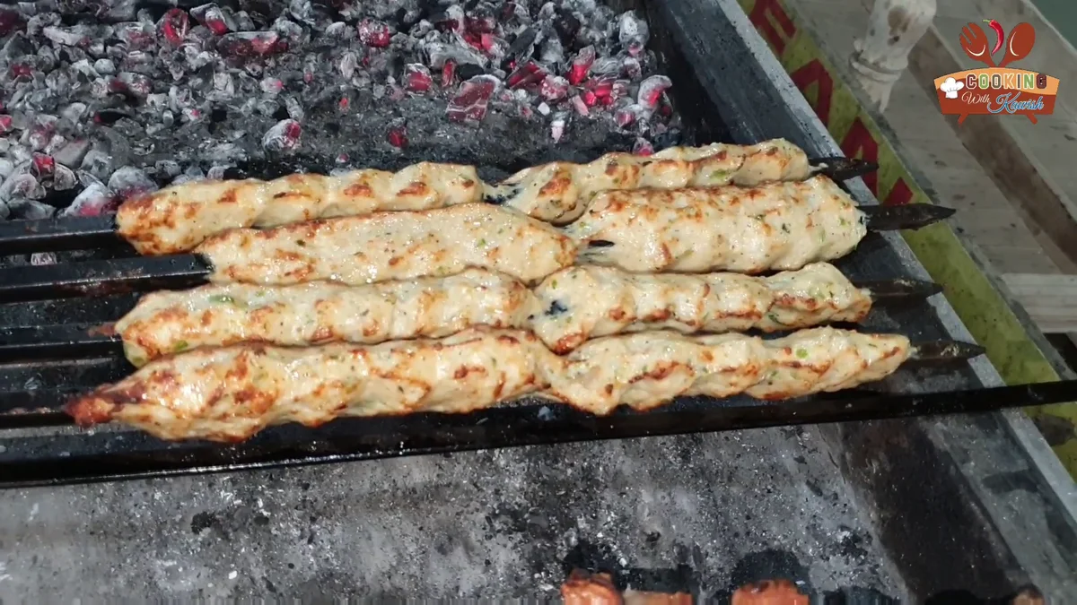 Golden chicken reshmi kababs on skewers over the coals