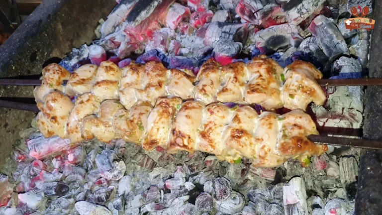 Golden chicken malai boti skewers over glowing charcoal