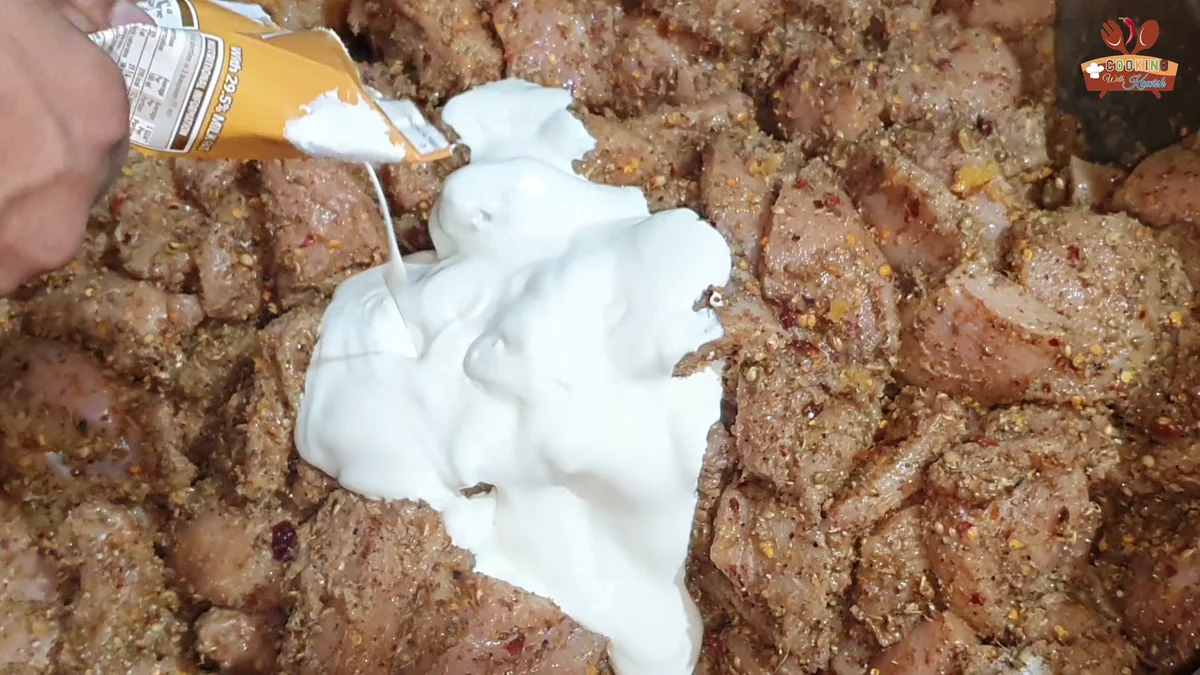 Fresh cream being poured over the spiced chicken